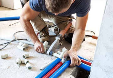 Professional plumber working with colored PVC pipes